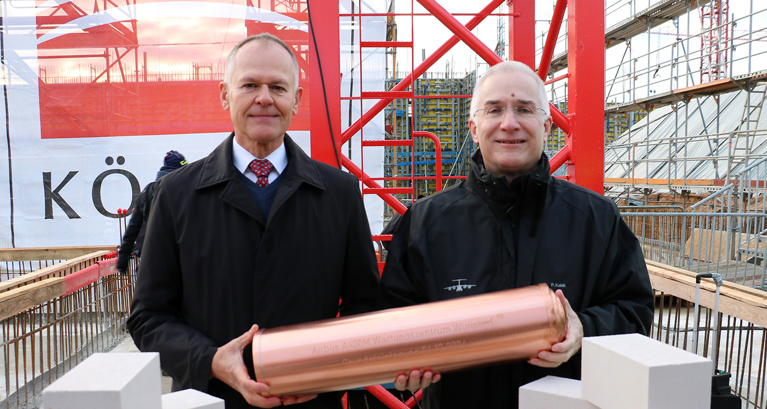 Matthias Fink (li.) und Peter Kalak von Airbus DS mit der traditionellen Kartusche bei der Grundsteinlegung für das A400M Wartungszentrum. (Foto: Lindhorst)