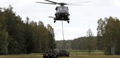 Transporthubschrauber NH90 fliegt Geländefahrzeug als Außenlast in Landezone. (Foto © Bw/Andreas Bernstein)