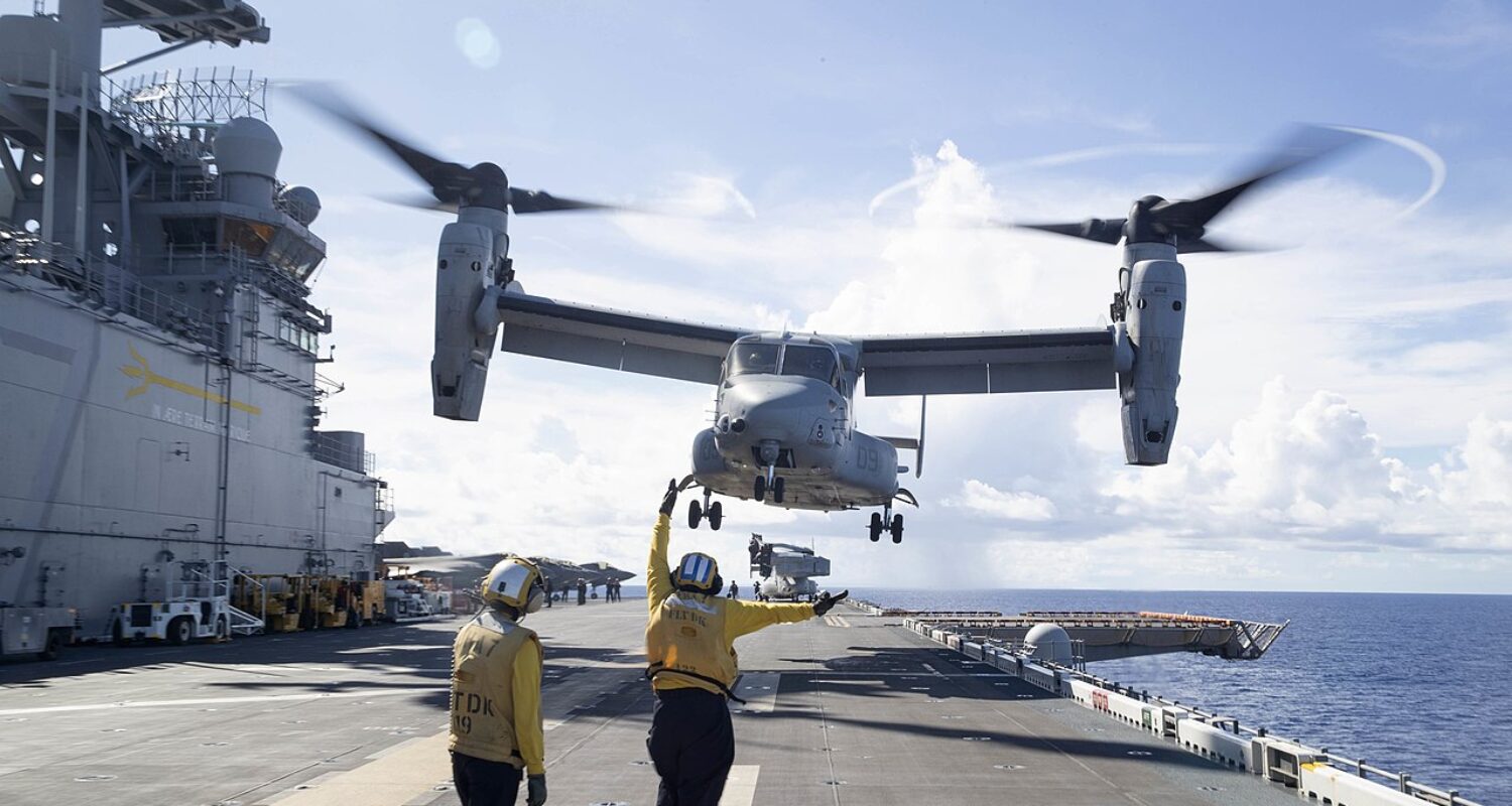 Ein MV-22 Osprey Kipprotorflugzeug des U.S. Marine Corps über dem Amphibienträger USS Tripoli, der aktuell für einen möglichen Einsatz im Irankrieg Richtung Naher Osten verlegt.